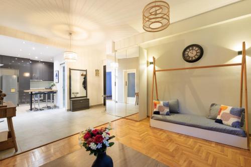 Una sala de estar con un sofá y un reloj en la pared. en Aiolos Elegant retro suite in GLYFADA centre, en Atenas