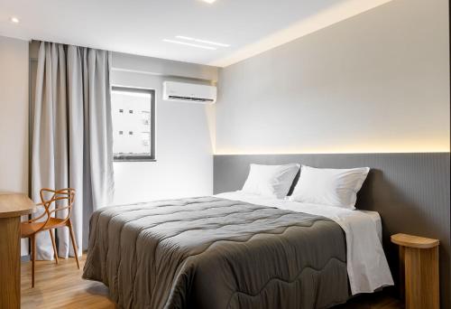 a bedroom with a bed and a desk and a window at Villano Hotel in Blumenau