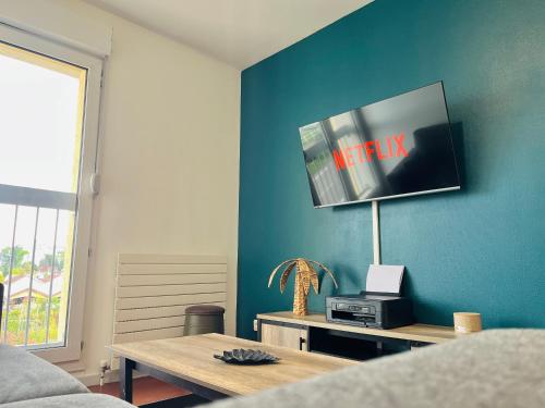 un salon avec une télévision sur un mur bleu dans l'établissement Grand appart 4 chambres, à Épinal