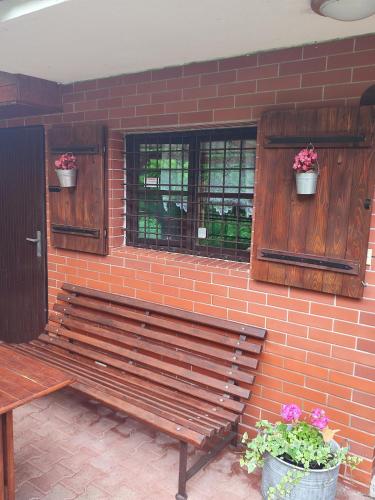 a wooden bench against a brick wall with potted plants at Chata pod Luhačovickou přehradou in Pozlovice