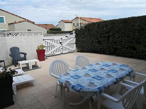une table et des chaises assises sur une terrasse dans l'établissement Maison de vacances climatisée 600m de la mer Cour privative et parking, à Port-la-Nouvelle