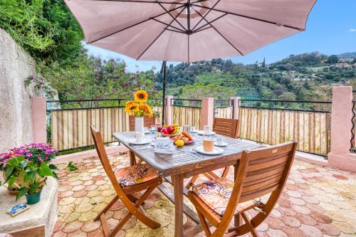 - une table en bois avec un parasol sur la terrasse dans l'établissement Maison Baousset - Happy Rentals, à Menton