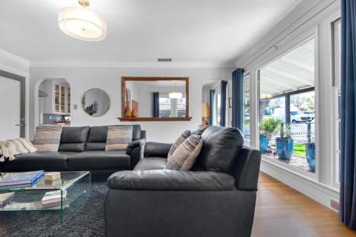 a living room with a leather couch and a table at MIDCENTURY MANOR-Hot Tub & 5 Blocks to Town Center in Paso Robles