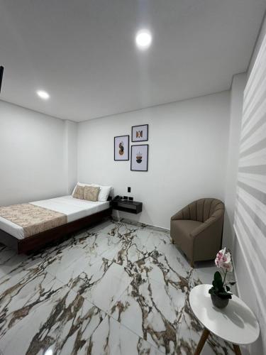 a bedroom with a bed and a chair and a marble floor at ZAFIRO HOTEL in Doradal