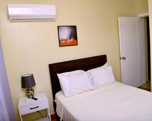 a bedroom with a bed with white pillows and a clock at Peaceful 2 Bed Apartment - Pool & Private Beach Access in Punta Cana