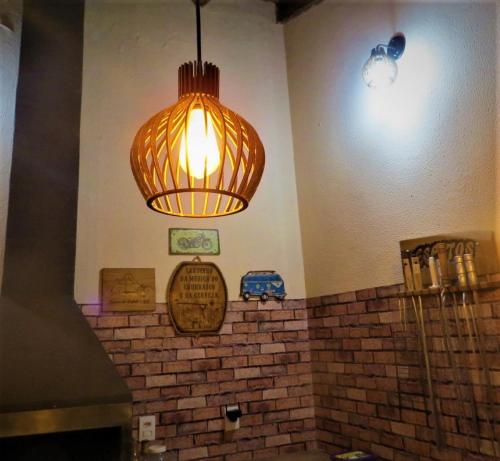 a light hanging over a brick wall in a room at Hostel ElianeMS Quartos Privativos com Banheiro in Campo Grande
