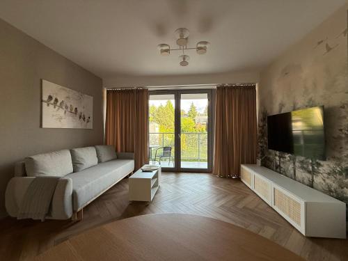 a living room with a couch and a flat screen tv at Apartament Forest Elegance in Charzykowy