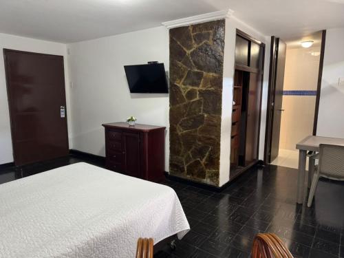 a hotel room with a bed and a stone wall at Vallclaire Suites in Barranquilla