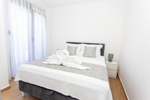a white bedroom with two swans towels on a bed at Apartments Ivo Herceg Novi in Herceg-Novi