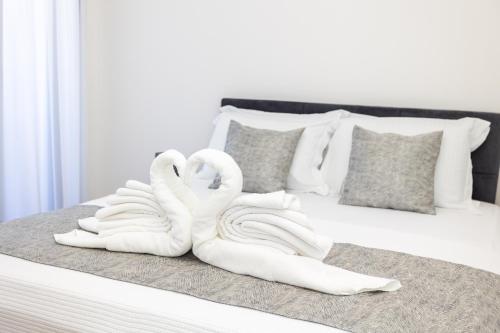 two white swans sitting on top of a bed at Apartments Ivo Herceg Novi in Herceg-Novi