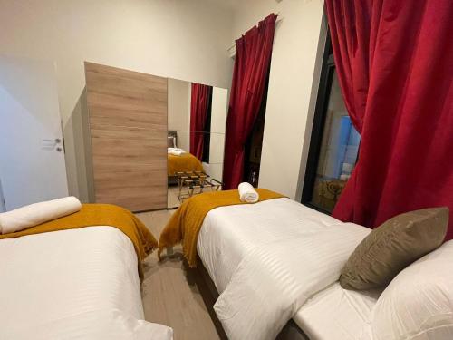 two beds in a room with red curtains and a mirror at OneLuxStay near Antwerp Central in Antwerp