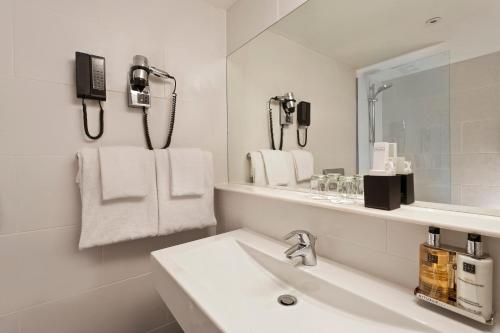 a bathroom with a sink, mirror, and towel rack at Wyndham Stuttgart Airport Messe in Stuttgart