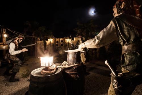 a man standing next to a barrel with a candle at Hôtel Cap Pirate in Cap d'Agde