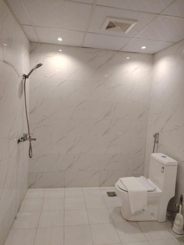 a white bathroom with a toilet and a shower at As Salam Apartment in Al Madinah