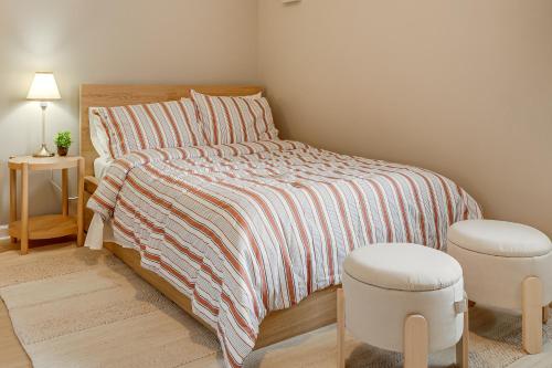 布莱恩Convenient Studio Stay Easy Access to Twin Cities的卧室里有一张床，床边有条纹棉被，还有凳子