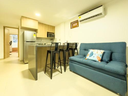 Una sala de estar con un sofá azul y una cocina. en Cómodo estudio con AC en frente de una cancha, en Santa Fe de Antioquia