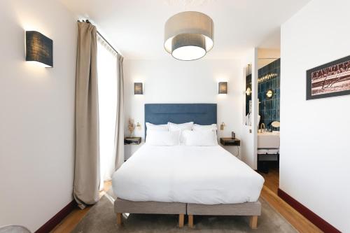 una camera da letto con un letto bianco e una grande finestra di Villa Lorenzo Chambres & Restaurant Barcelonnette Hotel a Barcelonnette