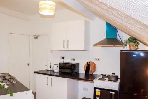 a kitchen with white cabinets and a black refrigerator at Entire Cosy 1 Bedroom Flat in Brightside
