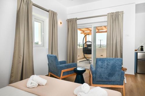 アダマスにあるAegean Blue - Volia Deluxe apartのベッド1台、椅子2脚、窓が備わる客室です。