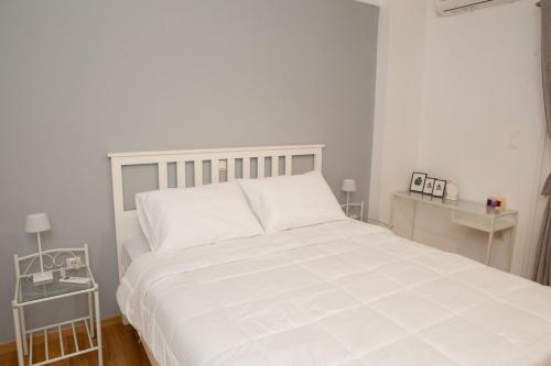 een wit bed in een witte slaapkamer met 2 tafels bij Modern 1 bedroom apartment in Athene