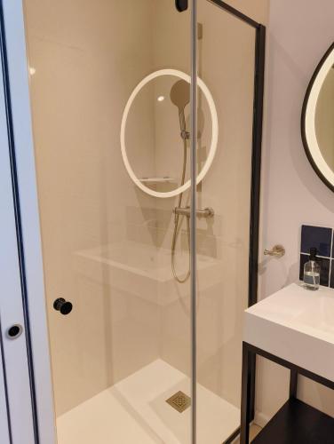 une douche avec une porte vitrée à côté d'un lavabo dans l'établissement LES PATICHERES - La Grange avec accès à la piscine, à Biville-la-Baignarde