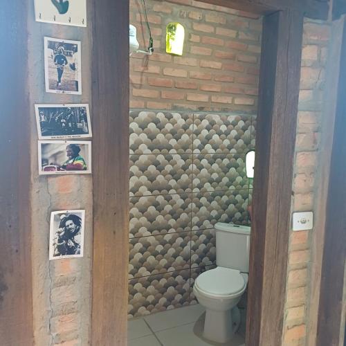a bathroom with a toilet and a brick wall at Claudinha chalés in Conceição da Ibitipoca