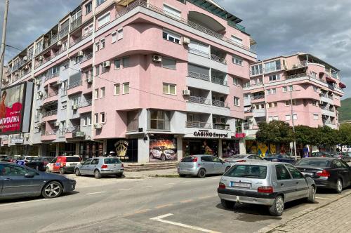 a pink building with cars parked in a parking lot at Apartments FANTASY with Free Parking in Ohrid
