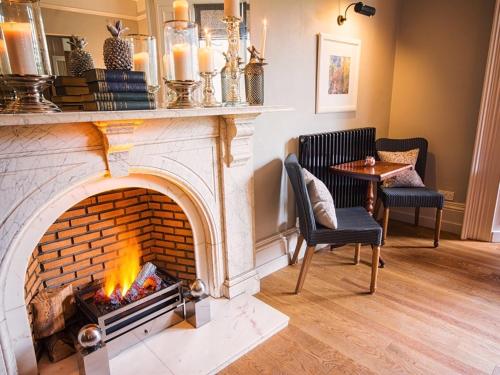 a fireplace in a living room with two chairs and a table at Eslington Villa in Gateshead