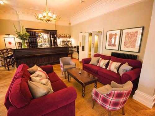 a living room with two red couches and a piano at Eslington Villa in Gateshead