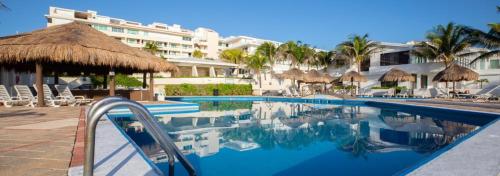 a swimming pool with umbrellas and a resort at Espacioso condo en Cancun - con acceso a playa in Cancún