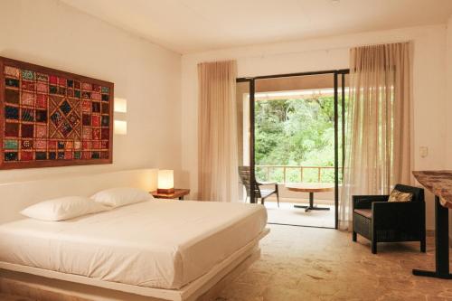 a hotel room with a bed and a balcony at Hotel Hukumeizi Minca in Minca