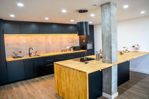 une cuisine avec des armoires noires et un comptoir en bois dans l'établissement La Grange de Saulzoir, à Saulzoir