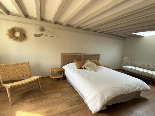 a bedroom with a bed and a chair at Le Nid de Plumetot - Maison de Charme en Normandie in Plumetot