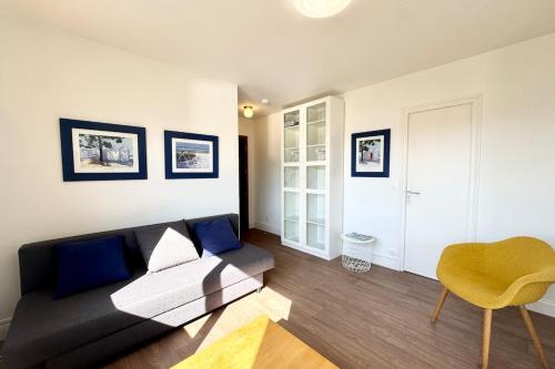 - un salon avec un canapé noir et un fauteuil jaune dans l'établissement Charmant Studio - Bourg & plages à pied, à Larmor-Plage
