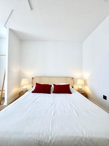 a bedroom with a large white bed with two red pillows at Charmant T2 - Plein coeur de Quimperlé in Quimperlé