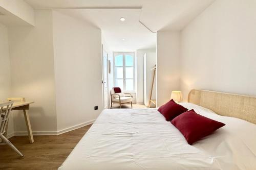 a bedroom with a large white bed with red pillows at Charmant T2 - Plein coeur de Quimperlé in Quimperlé