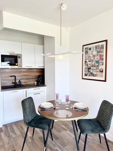 une table de salle à manger avec des chaises et une cuisine dans l'établissement Lovely ! Studio balcon - Vue océan 360, à Larmor-Plage