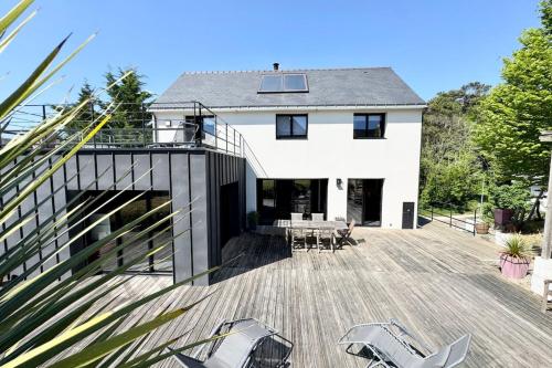 une maison blanche avec une terrasse et des chaises dans l'établissement Villa bord de mer Terrasse & accès plage à pied, à Guidel