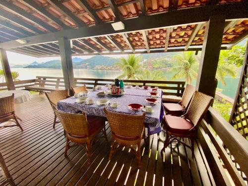 a dining table on a deck with a view of the ocean at Vista dos sonhos na beira do mar de Angra com pier in Angra dos Reis