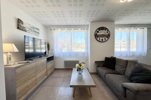 un salon avec un canapé et une télévision dans l'établissement Élégant T2 - Les pieds dans l'eau, à Guidel