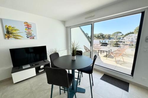 un salon avec une table, des chaises et une télévision dans l'établissement T2 contemporain - Balcon - Vue mer panoramique, à Guidel