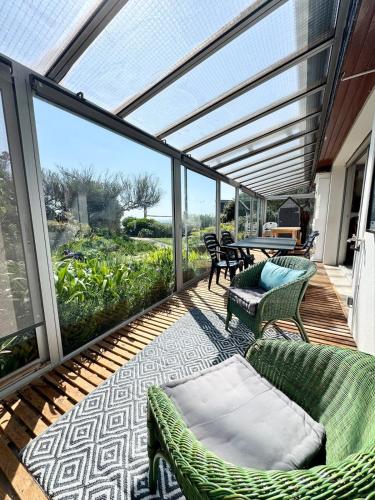 - une terrasse couverte avec un canapé, des chaises et une table dans l'établissement Spacieuse maison au bord des plages, à Ploemeur