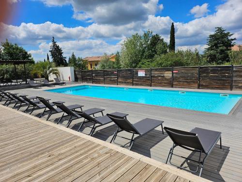 una piscina con tumbonas junto a una terraza de madera en Studio Le Paradis Vert Aix-en-Provence, parking, piscine, en Aix-en-Provence