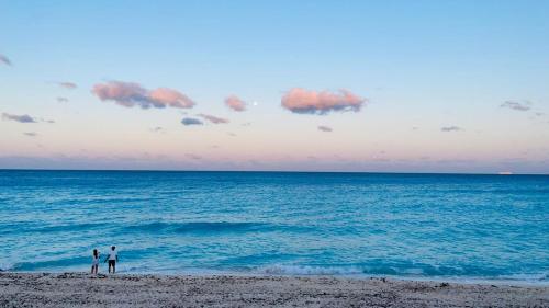 two people standing on the beach looking at the ocean at Espacioso condo en Cancun - con acceso a playa in Cancún