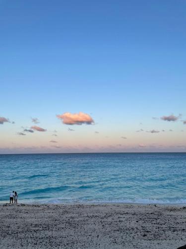 a group of people standing on a beach near the ocean at Espacioso condo en Cancun - con acceso a playa in Cancún