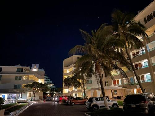 a street with palm trees and buildings at night at Espacioso condo en Cancun - con acceso a playa in Cancún