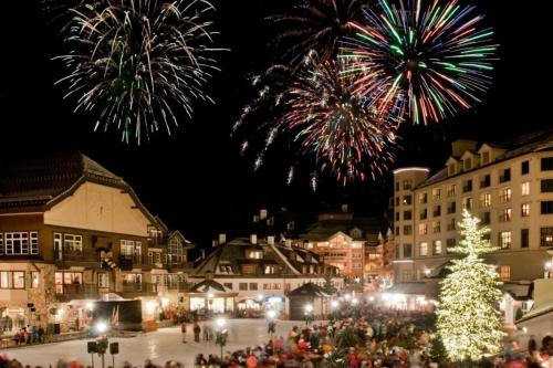 a crowd of people standing around a christmas tree with fireworks at Luxe 4 Bedroom Beaver Creek Lodge Condo With Ski In, Ski Out Access in Beaver Creek