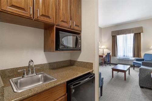 a kitchen with a sink and a living room at Best Western Plus Executive Hotel & Suites in Sulphur