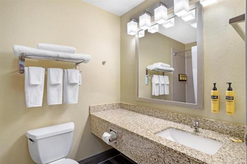a bathroom with a toilet and a sink and a mirror at Best Western Plus Executive Hotel & Suites in Sulphur