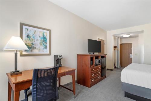a hotel room with a desk and a bed and a bed and a room with at Best Western Plus Executive Hotel & Suites in Sulphur